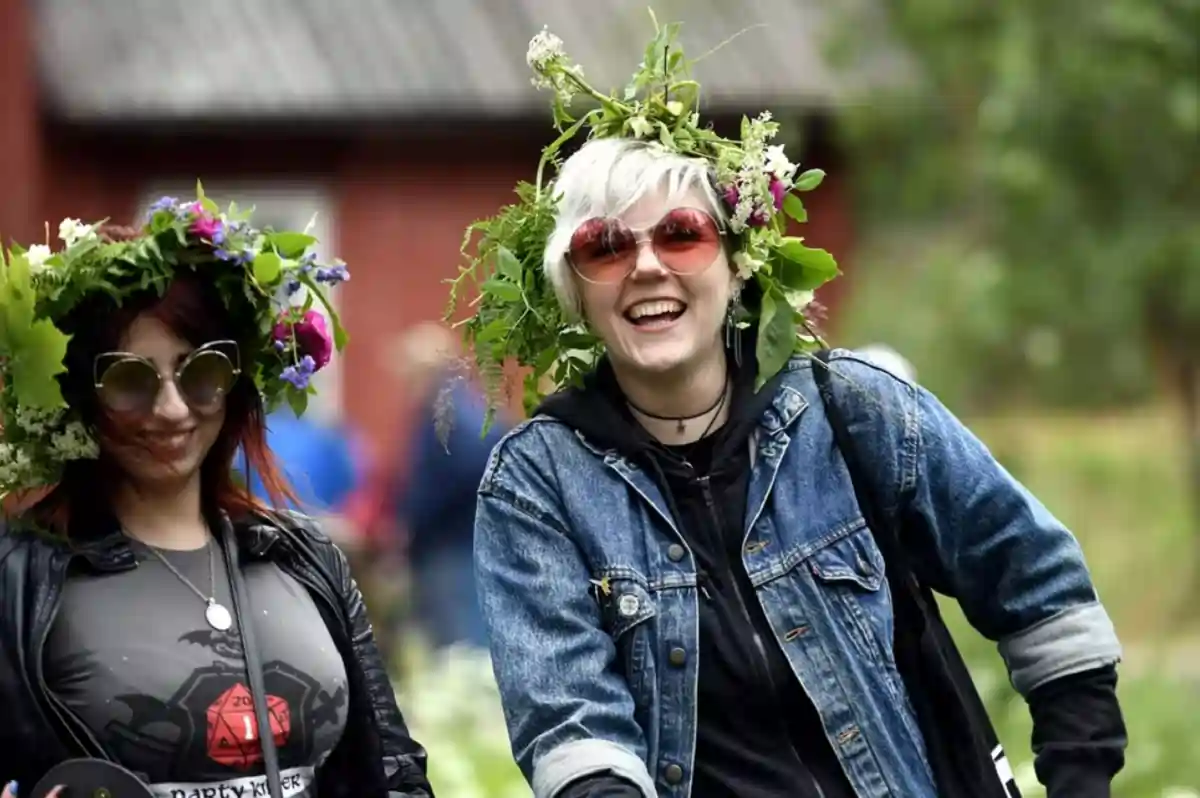 Finland's Happiness Paradox: Unveiling Real Sentiments 1 Girls with flower garlands celebrate the summer solstice during the Midsummer Eve festival at the Seurasaari open-air museum in Helsinki, Finland.